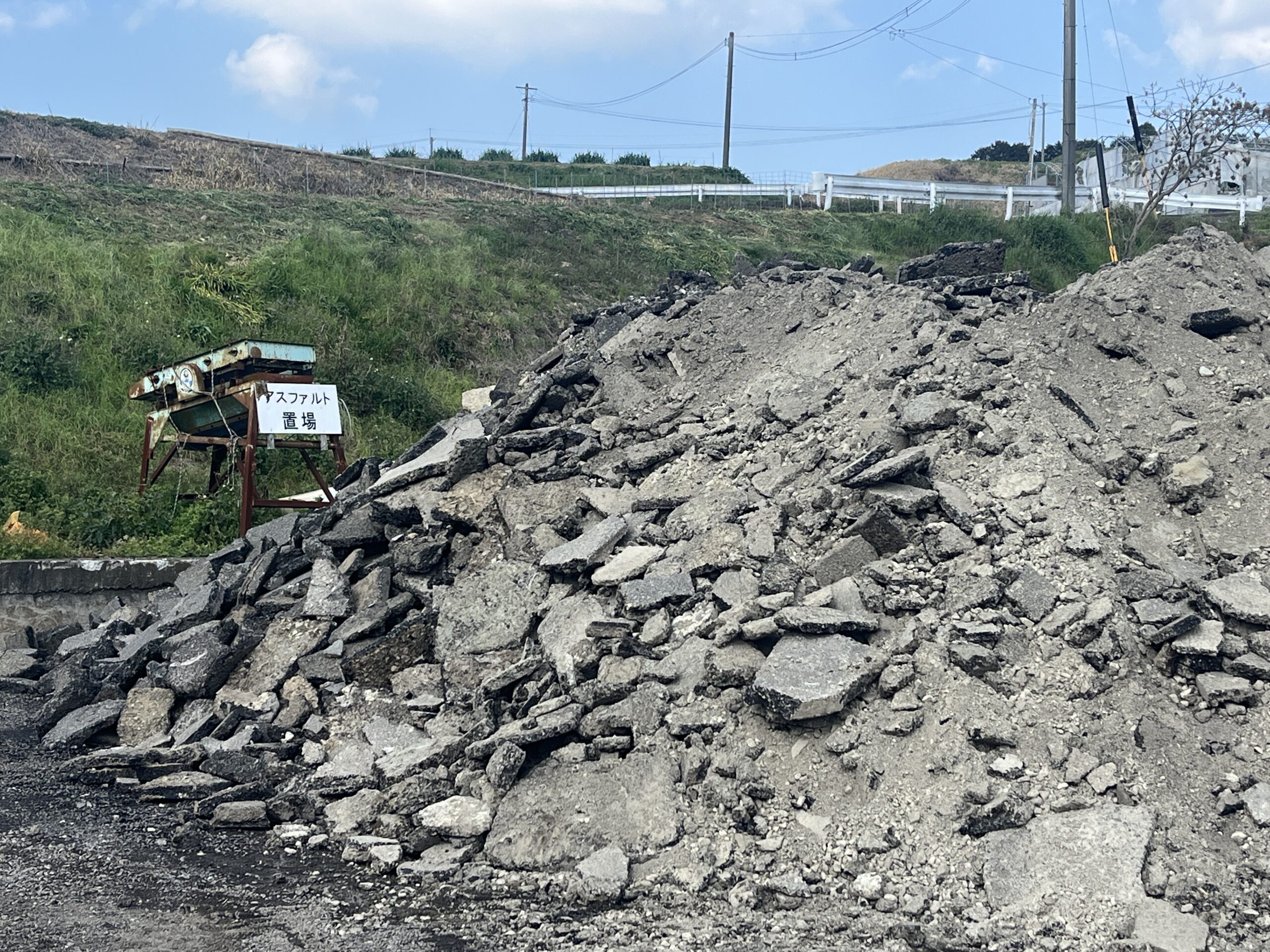 アスファルト置場の看板と解体・舗装工事から発生したアスファルトがらの集積状況