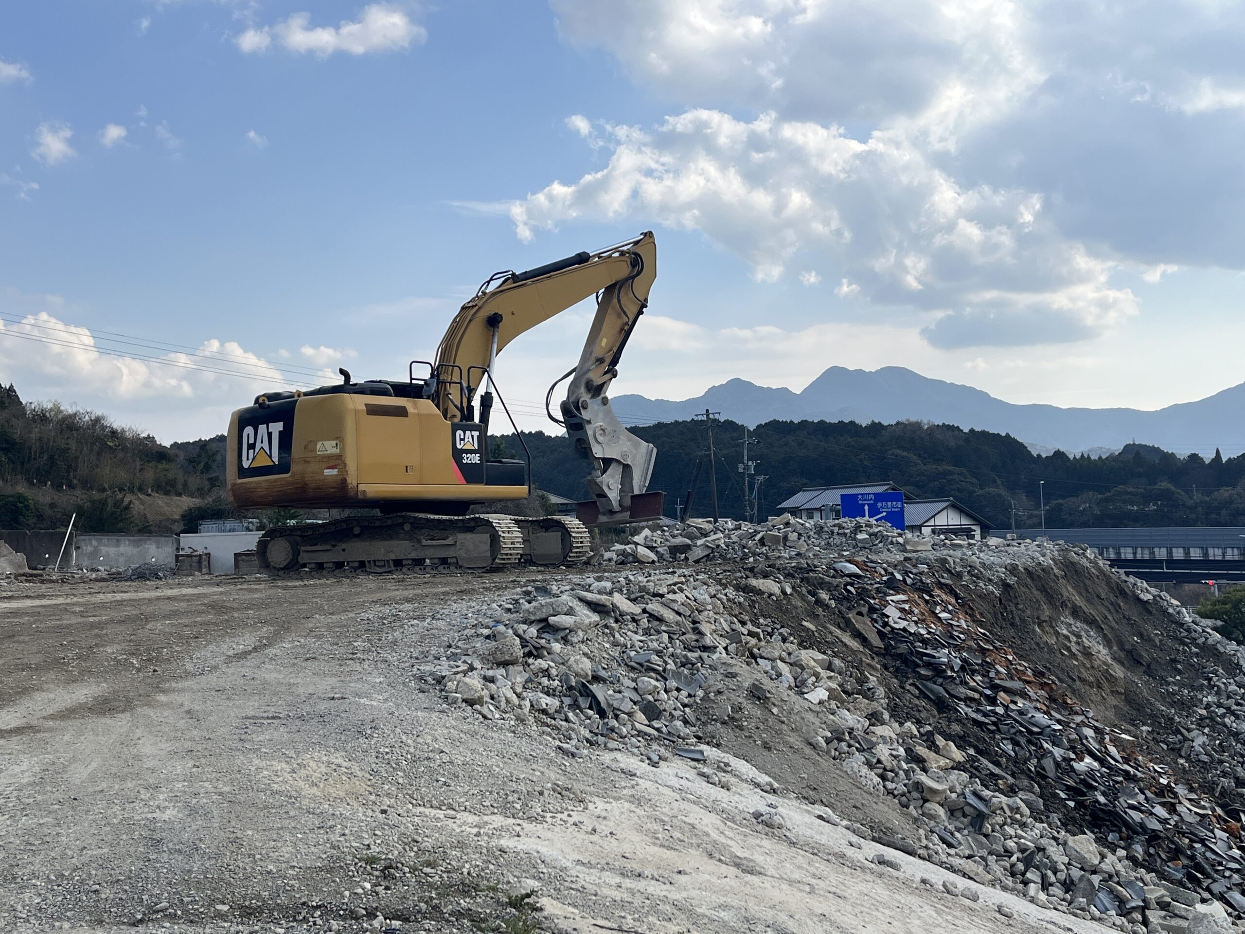 CAT 320E油圧ショベルがコンクリートがら・瓦くず等の廃材山で集積・整備作業を行っている様子